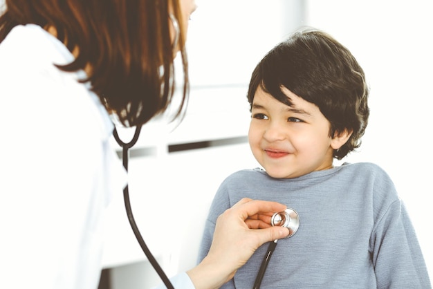 Doctorwoman esaminando un paziente bambino con uno stetoscopio Ragazzo arabo carino su appuntamento con il medico Concetto di medicina