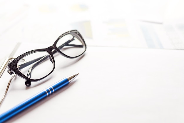 Documenti con penna e occhiali sul tavolo dell'ufficio Immagine ravvicinata Concetto di conclusione Focus su occhiali sfondo sfocato