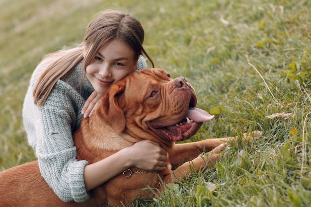 Dogue de Bordeaux o mastino francese con la giovane donna al prato del parco all'aperto.