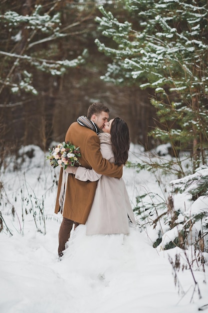 Dolce bacio degli sposi in inverno tra l'oscuro bosco di pini 871