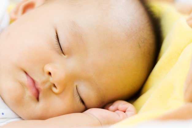 dolce bambino asiatico che dorme sul letto a casa