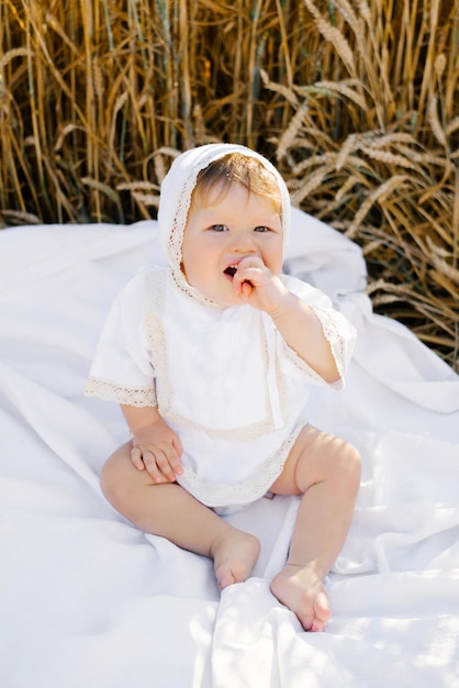 Dolce bambino di otto mesi seduto su una coperta in un campo