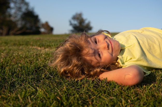 Dolce bambino felice che gioca su un'erba in un parco in primavera Ridendo godendo di fresco Bambini divertenti