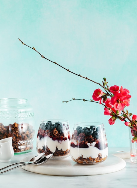 Dolce del mattino con muesli in un bicchiere con yogurt, marmellata e frutti di bosco freschi.