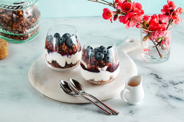 Dolce del mattino con muesli in un bicchiere con yogurt, marmellata e frutti di bosco freschi.