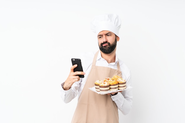 Dolce del muffin della tenuta del giovane che pensa e che invia un messaggio