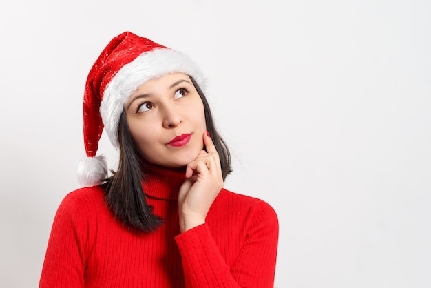 Dolce giovane donna sognante in un maglione rosso e cappello di Natale.