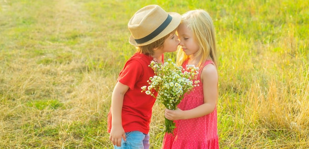 Dolce infanzia bambini innamorati che baciano i bambini che si divertono in campo sullo sfondo della natura sprin