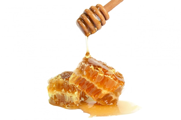 Dolce miele che gocciola sul favo isolato su bianco