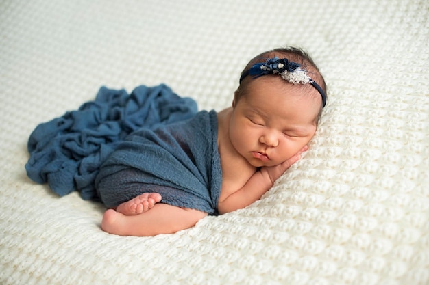 Dolce neonata in pagliaccetto che dorme sul lettino rotondo