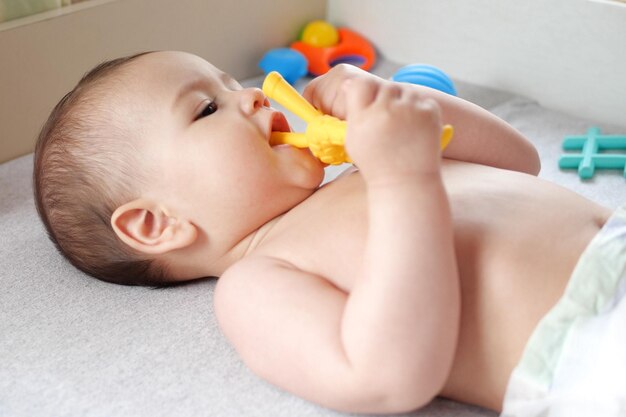 Dolce neonato adorabile che gioca con un giocattolo a sonagli colorato bambino con denti di sei mesi bel ritratto di bambino su bianco con giocattolo denti