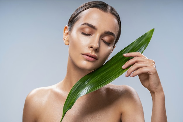 Dolce ragazza in posa per la macchina fotografica su sfondo grigio