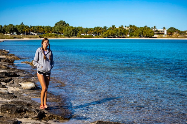 dolce ragazza in trecce cammina sulla spiaggia di Coral Bay all'alba, australia occidentale