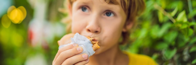 Dolce ragazzino caucasico che mangia frittelle e beve il formato lungo dell'insegna del succo d'arancia