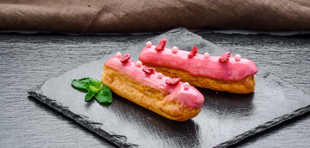 Dolce tradizionale francese. Eclair con glassa al cioccolato e lamponi.