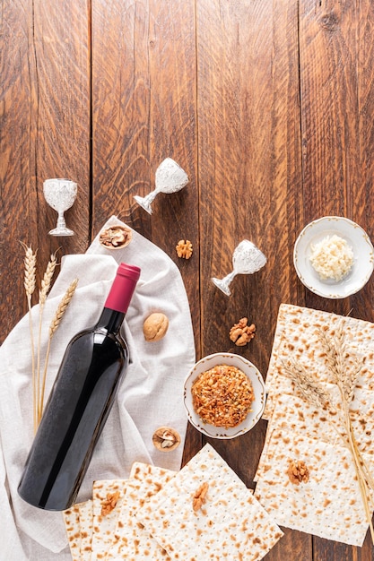 Dolcetti tradizionali per la festa della Pasqua ebraica noci matzoth una bottiglia di vino radice di prezzemolo Vista verticale dall'alto Sfondo in legno