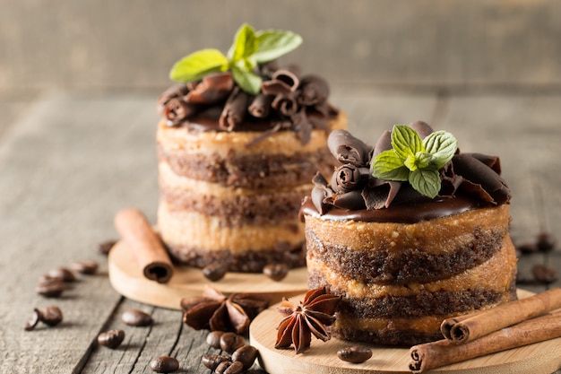 Dolci al cioccolato fondente sul bordo nero slattern con menta, cannella, chicchi di caffè su un fondo di legno. Concetto di cibo gustoso dessert.