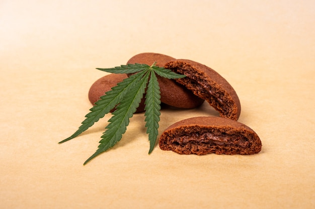 Dolci alla cannabis, biscotti al cioccolato con pianta di marijuana a foglia verde.