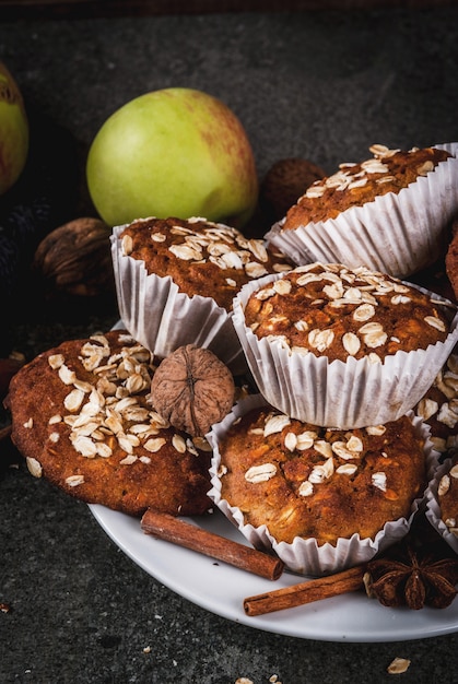 Dolci autunnali invernali. Cibo vegano. Sano biscotti da forno fatti in casa, muffin con noci, mele, fiocchi d'avena. Atmosfera casalinga accogliente, coperta calda, ingredienti. Tavolo in pietra scura.