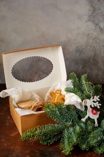 Dolci biscotti di Natale, un barattolo di caramello si trovano in una confezione regalo accanto a un ramo di abete e un giocattolo di cervo