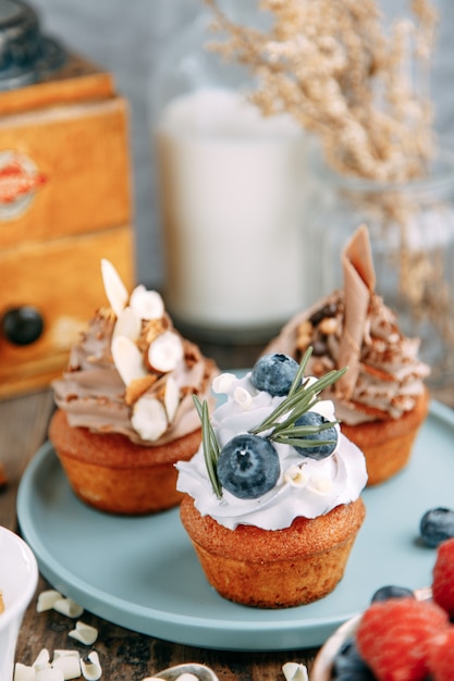 Dolci con panna, mirtilli e cioccolato. Disposizione di dessert con noci su un tavolo di legno.