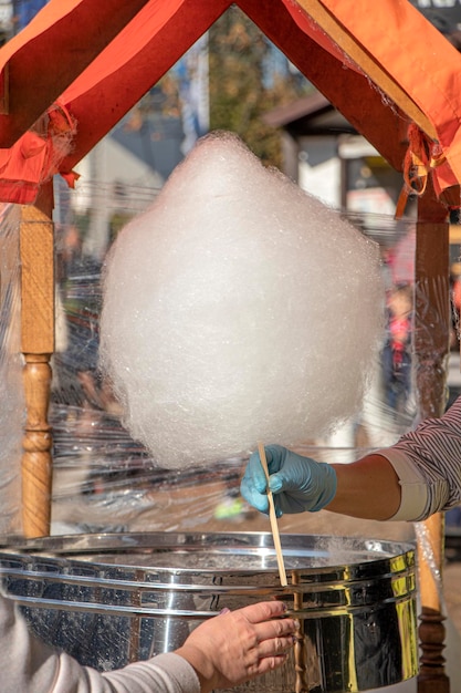 Dolci di strada che comprano zucchero filato in una fiera di strada giovane donna tiene in mano zucchero filato