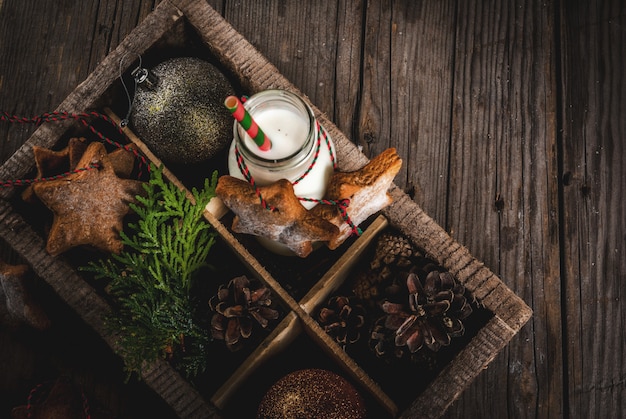 Dolci e dolcetti di Natale, bottiglia con latte per Babbo Natale con biscotti di panpepato stelle con corda di decorazione e decorazioni natalizie, in scatola di legno, legno vecchio, vista dall'alto