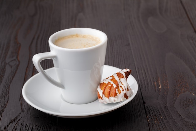 Dolci e tazza di caffè saporiti su fondo di legno