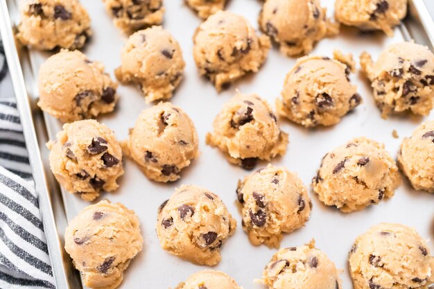 Dolci fatti in casa di pasta per biscotti con gocce di cioccolato su una teglia.