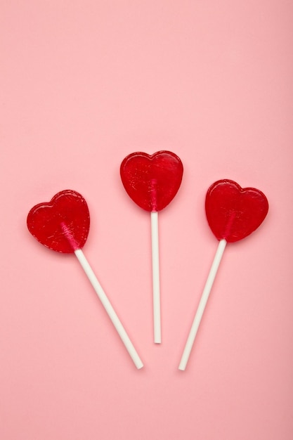 Dolci lecca-lecca a forma di cuore su sfondo rosa Celebrazione del giorno di San Valentino Foto verticale
