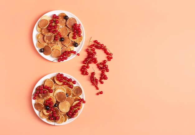 Dolci mini frittelle con ribes rosso e nero su piatti bianchi su una pesca