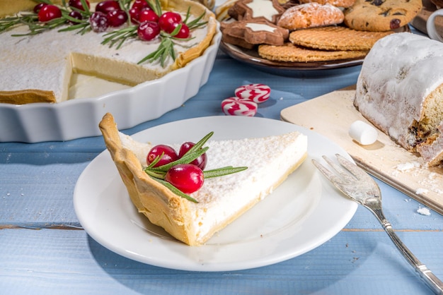 Dolci natalizi fatti in casa, torta di formaggio dolce con zucchero a velo, mirtilli rossi e rosmarino. Sfondo di cottura festivo di Natale e Capodanno