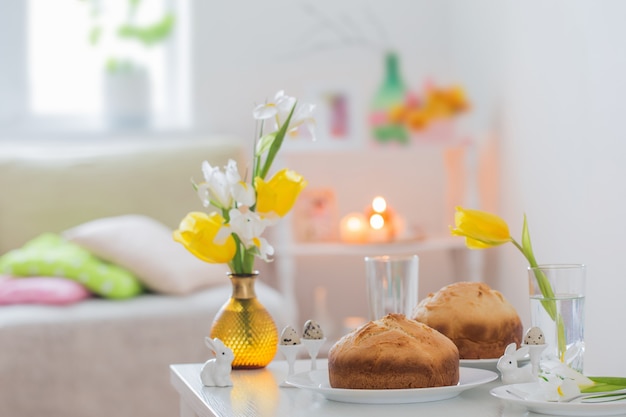 Dolci pasquali con fiori primaverili in interni bianchi