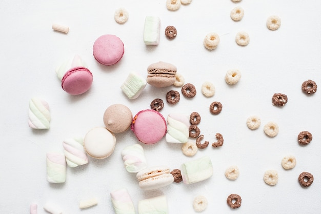 Dolci su sfondo bianco. Amaretti colorati, zefiri e assortimento di cereali per la colazione