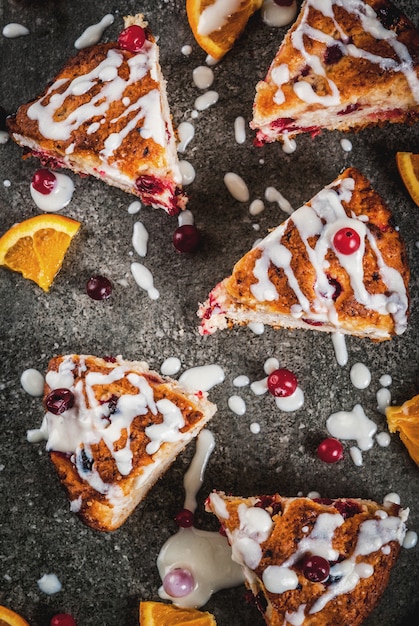 Dolci tradizionali inglesi inglesi. Torta di biscotti con mirtilli rossi e scorza d'arancia, con glassa bianca dolce, tavolo in pietra nera