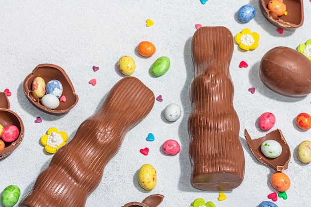 Dolci tradizionali pasquali con uova, cioccolato, coniglio, decorazioni commestibili festive, ricerca per bambini, alla moda, duro, chiaro, scuro, ombra, pietra chiara, sfondo di cemento, piatto, laico, primo piano