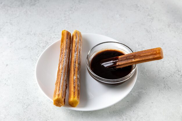 Dolci tradizionali spagnoli churros e salsa al cioccolato su sfondo grigio