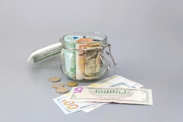 Dollari americani e banconote in euro in un barattolo di vetro Banconote e monete in un salvadanaio Risparmia denaro