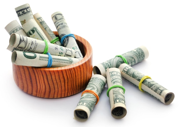 Dollaro americano arrotolato in una ciotola di legno su sfondo bianco