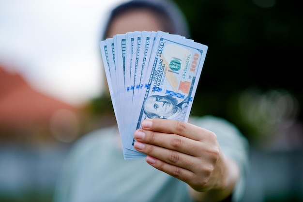 Dollaro nelle mani di una donna asiatica Risparmio Investimenti Stipendio Reddito Flusso di cassa Felicità, successo finanziario e investimenti