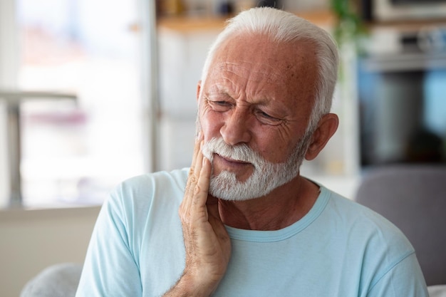 Dolore ai denti e odontoiatria Senior uomo che soffre di terribili denti forti dolore toccando la guancia con la sensazione di mano doloroso mal di denti cure odontoiatriche e concetto di salute