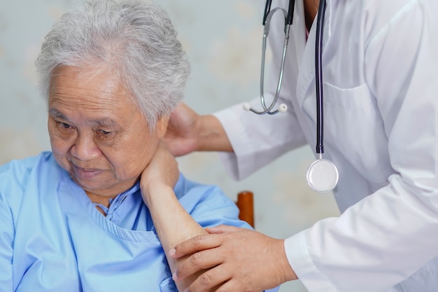 Dolore al collo paziente della donna senior asiatica mentre sedendosi nell'ospedale.