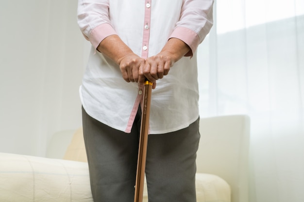 Dolore al ginocchio della donna senior con il bastone, problema di sanità del concetto senior