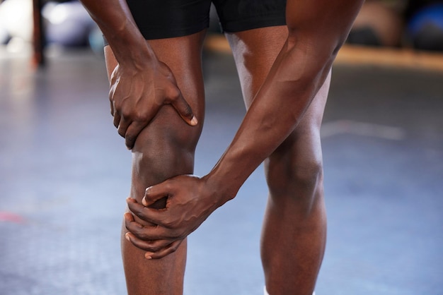 Dolore al ginocchio delle mani e uomo in palestra con infortunio ferito o dolorante durante l'allenamento fitness e l'esercizio sullo spazio del mockup Incidente sportivo e gambe del ragazzo con artrite muscolare o infiammazione durante l'allenamento