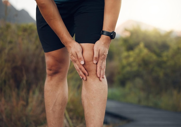 Dolore al ginocchio gambe e artrite dell'atleta uomo corridore e allenamento allenamento o esercizio su sentiero escursionistico all'aperto Primo piano problema di frattura ossea lesioni muscolari e rischio per la salute del corpo per la terapia sportiva