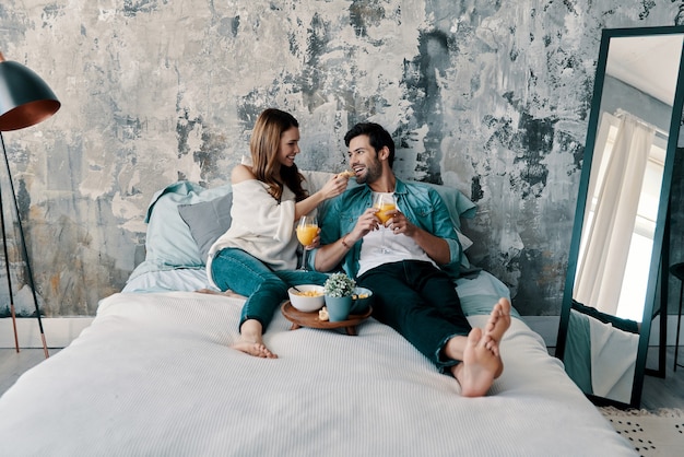 Domenica mattina spensierata. Bella giovane coppia che fa colazione mentre trascorre il tempo a letto a casa