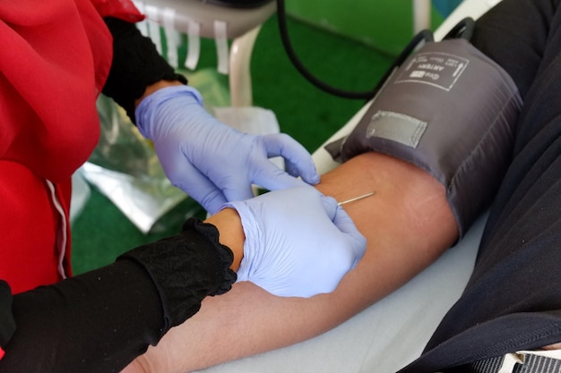 Donazione di sangue con un ago bloccato nel braccio Immagine del concetto per il donatore di sangue mondiale