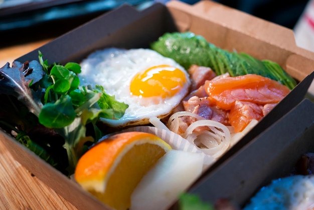 Donburi di salmone con uovo in cima. Pranzo al sacco giapponese.