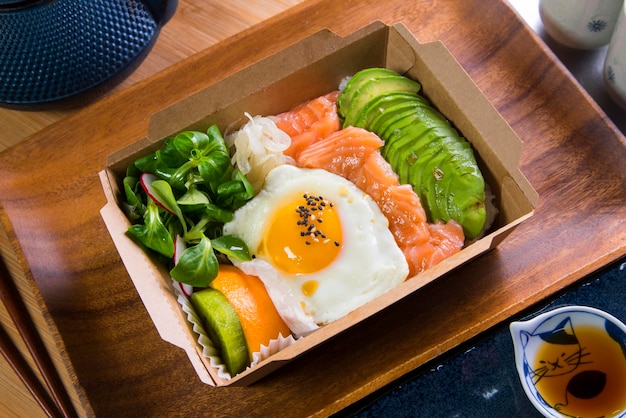 Donburi di salmone con uovo in cima. Pranzo al sacco giapponese.