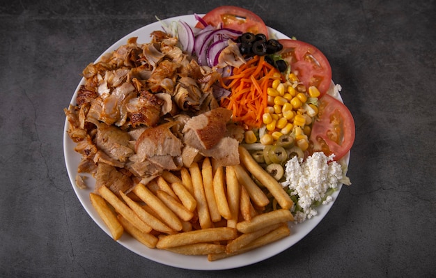 Doner kebab o gyros su un piatto con patatine fritte e insalata